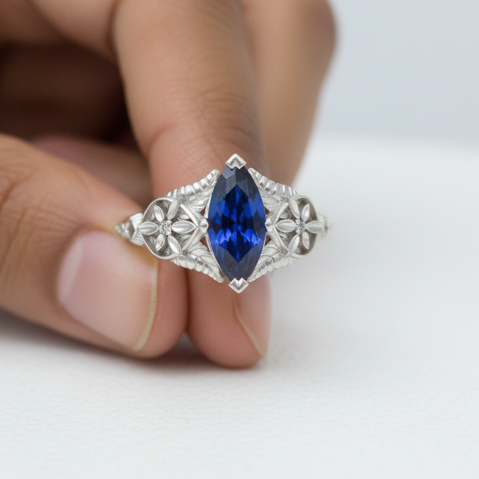 Silver ring with a blue gemstone held between fingers on a white background