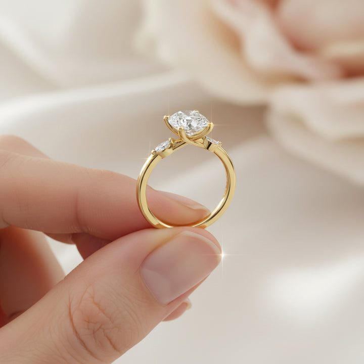 Gold ring with an oval diamond held between fingers against a soft background