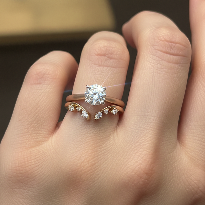 A gold ring with small clear gemstones displayed on a white ring stand, with a finger holding the stand at the bottom right.